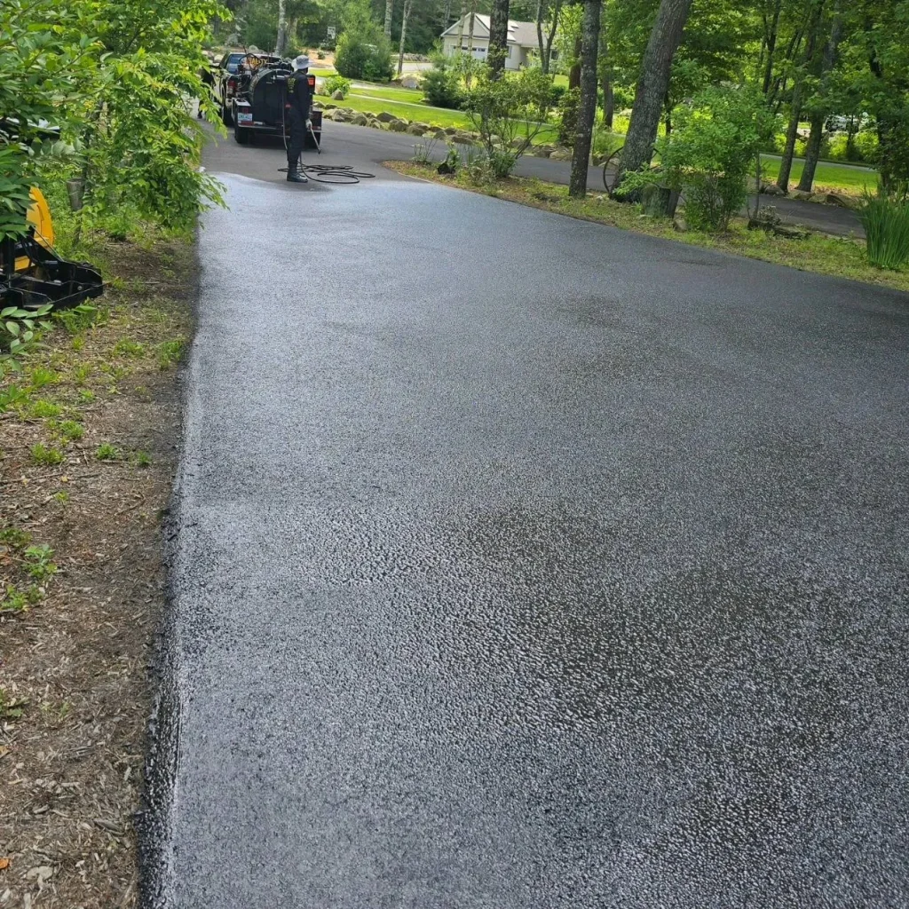 Sealcoating process in action, demonstrating application techniques for residential driveways